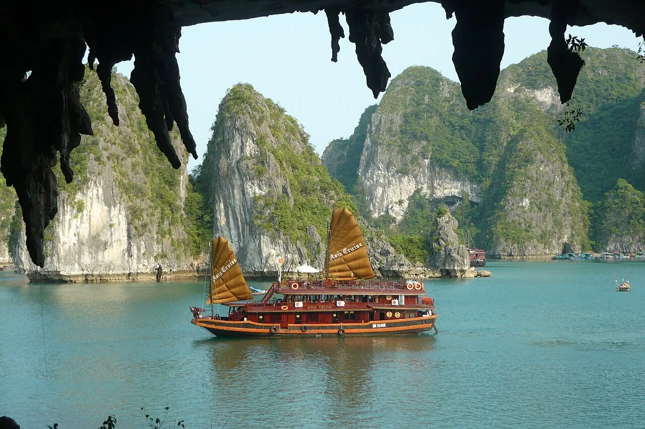 Traditional junk boat cruising between limestone islands