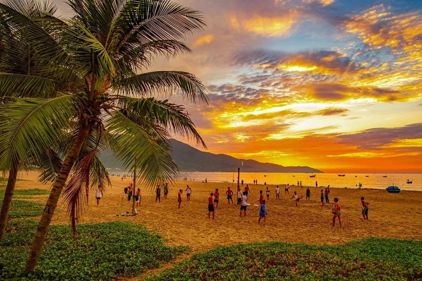 Da Nang's golden sand beach at sunset with the Dragon Bridge in the background