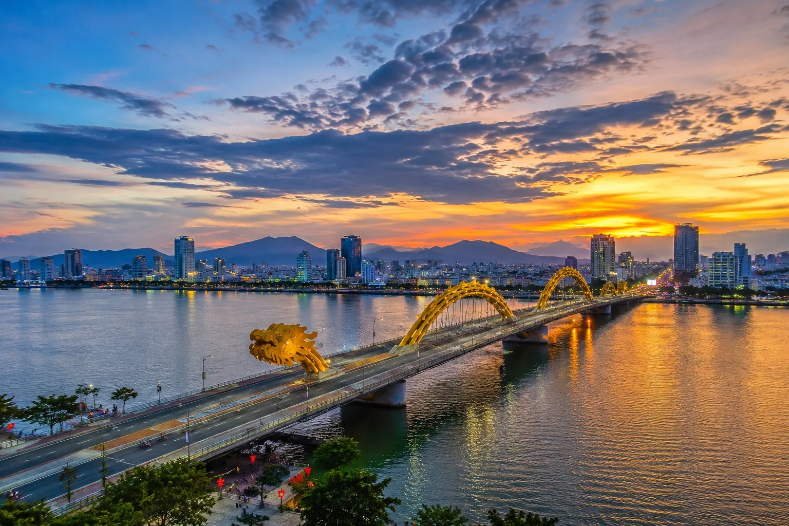 Da Nang's golden sand beach at sunset with the Dragon Bridge in the background